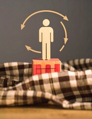 A wooden figure of a person stands atop a small wooden structure, surrounded by circular arrows