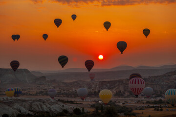 Naklejka premium Hot air balloon flying over rocky landscape at sunrise in Cappadocia. Turkey