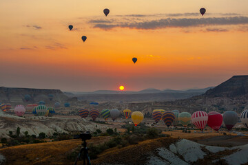 Hot air balloon flying over rocky landscape at sunrise in Cappadocia. Turkey