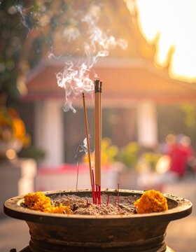 Traditional balinese canang sari religious offering in front of blurred temple in sunlight.