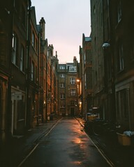 Obraz premium Narrow Urban Alleyway at Dusk with Warm Street Lighting