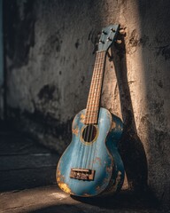 Obraz premium Vintage Blue Ukulele Leaning Against Wall in Dim Light