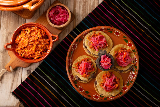 Panuchos, a typical dish from Yucatan, Mexico. A handmade, fried corn tortilla filled with beans, topped with cochinita pibil, pickled red onion, and habanero pepper.