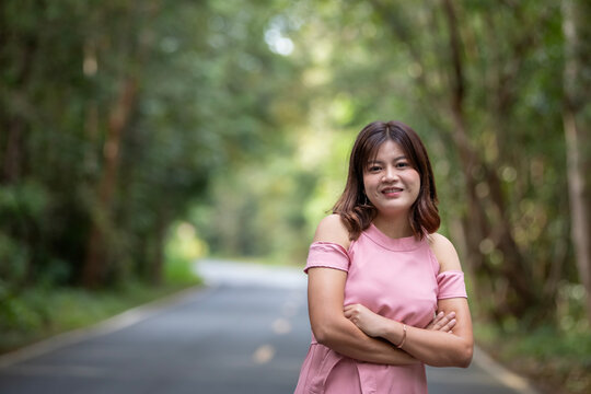 Portrait of a beautiful young woman walking on a road through a lush forest. Portrait of Asian.