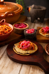 Panuchos, a typical dish from Yucatan, Mexico. A handmade, fried corn tortilla filled with beans, topped with cochinita pibil, pickled red onion, and habanero pepper.