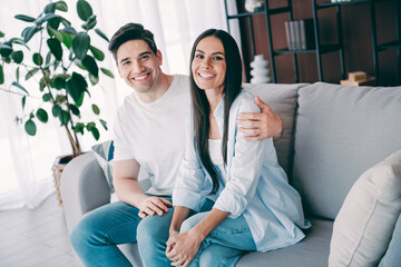 Young couple sitting happily on a comfortable couch in a cozy living room, expressing love and togetherness during a peaceful day indoors