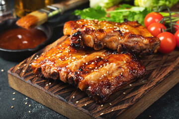 Spicy hot grilled spare ribs from a summer BBQ served with a hot chili pepper and fresh tomatoes