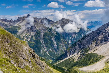 Alps mountains scenic landscape in summer. Austrian Alps scenery trekking path among the high mountain peaks in summer. Green mountain valleys with rocky peaks and lake in the Alps in Austria