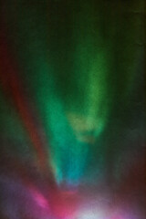 Soft Bright multicolored glare on dark rough textured cardboard. Soft rainbow light. Abstract colorful background. Colorful lens flare leak on a paper texture.