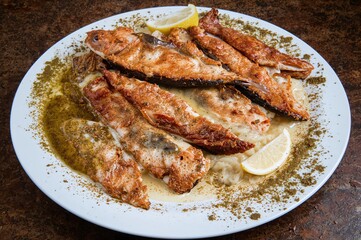 Crispy whole sardines served with lemon slices on a seafood assortment, traditional Mediterranean fare