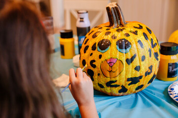 Elementary Age Girl Painting Cheetah Face on Pumpkin for Fall Halloween and Thanksgiving Holiday...