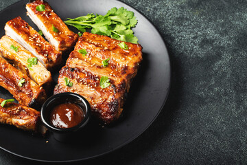 Hot grilled spare ribs from a summer BBQ served on a plate with sauce. Top view. Copy space