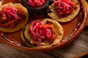 Panuchos, a typical dish from Yucatan, Mexico. A handmade, fried corn tortilla filled with beans, topped with cochinita pibil, pickled red onion, and habanero pepper.