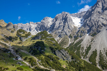 Alps mountains scenic landscape in summer. Austrian Alps scenery trekking path among the high mountain peaks in summer. Green mountain valleys with rocky peaks and lake in the Alps in Austria