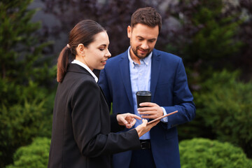 Coffee to go. Man with paper cup of drink and his business partner during meeting outdoors