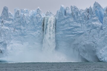 Waterfall from melting glacier ice plunges into ocean amid climate emergency in the Arctic
