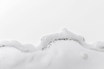 Foamy edge pattern on a light surface. Liquid soap spheres, bubbly foam texture. Soap suds bursting, pale background. Detailed soap bubble formation. Close-up of soap suds. Hygiene and cleanliness