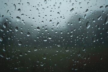 Raindrops sliding down a glass pane during a wet autumn monsoon day.
