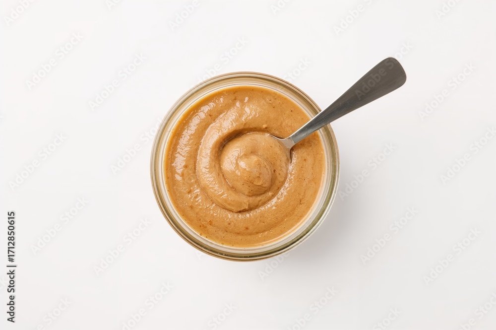 Poster top-down view of a glass container filled with peanut butter and a spoon on a white backdrop, with e