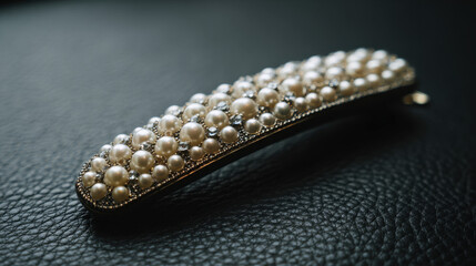 Elegant hair clip adorned with pearls resting on textured black leather surface, highlighting intricate design and luxurious aesthetic with subtle lighting effects.