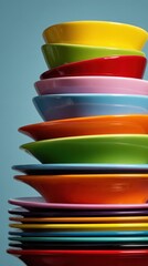 Stack of colorful glossy plates in vibrant rainbow hues arranged against a soft blue background in a modern pop art style