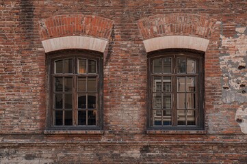 Fototapeta premium Pair of three-paneled mullioned windows set in an aged brick facade