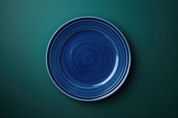 Blue round dinner plate on a deep greenish-turquoise backdrop with ample space for text.