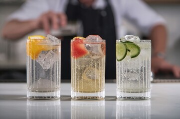 Classic long drink featuring gin and tonic served with various garnishes such as orange, grapefruit, or cucumber in individual glasses
