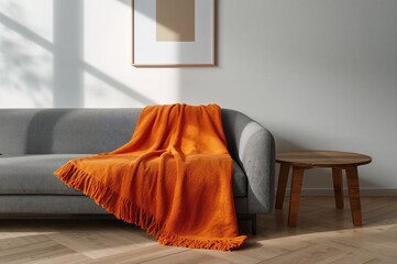 Grey couch with an orange throw in a contemporary living room featuring a wooden table and wall art. Authentic photograph