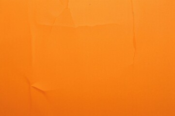 Background of crumpled paper in orange hue with wrinkled texture