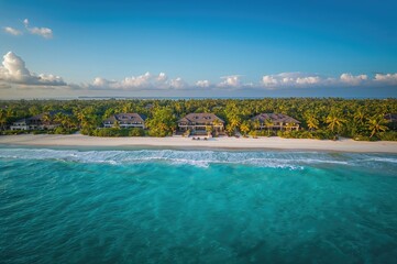 Expansive top-down perspective of shoreline with luxury homes, surf, and crystal-clear sea.