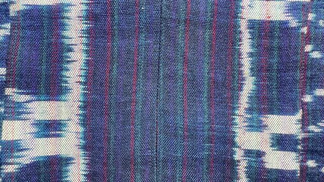 Handwoven ikat textile featuring colorful geometric patterns. Perfect for backgrounds, fashion, interior design, and cultural themes.