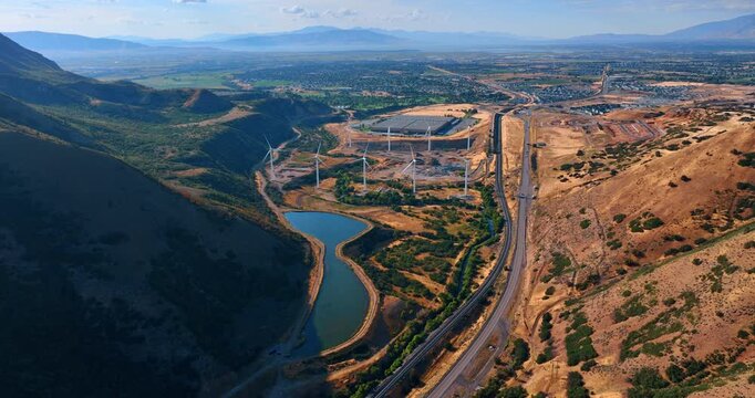 Approaching the pond and wind farm between the beautiful mountains. Aerial perspective on the urban landscape of Spanish Fork, Utah, USA.