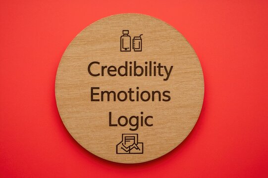 Circular wooden board featuring symbols and the terms Trust Feelings and Reason ethos pathos and logos idea on a crimson backdrop