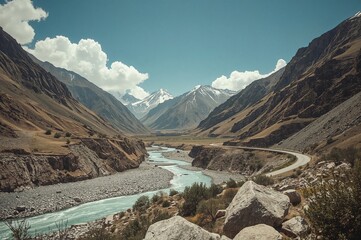 Old-school filtered hipster travel photo featuring rugged peaks, a river, and a road in a remote mountain valley.