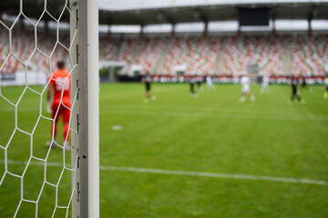 Detail of goal's post with net and game in the background.