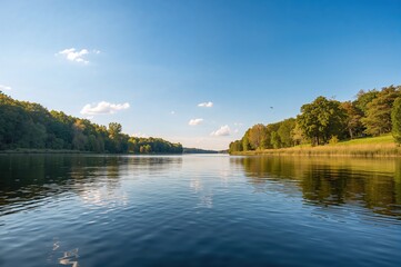 Obraz premium Symmetrical landscape featuring a river and lake with forest backdrop