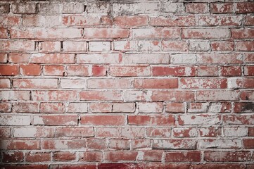 Naklejka premium Aged brick surface with red and white hues, damaged bricks, flaking plaster, retro texture, backdrop for signage, empty area