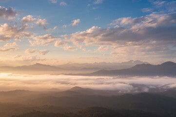 Obraz premium Misty clouds envelop towering peaks under a beautiful sky