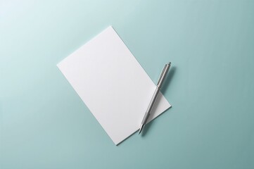 Overhead shot of empty writing paper and pen on a teal surface