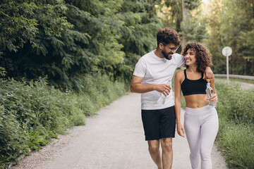 Happy multi ethnic couple walking and talking after training in a park