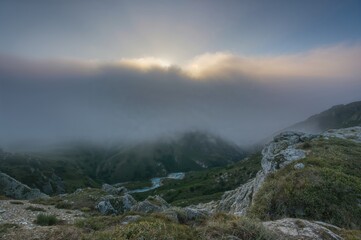 Foggy mountain valley with a river illuminated by sunlight