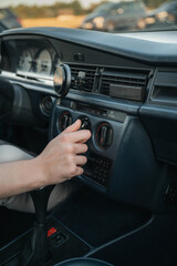 Fototapeta premium A human hand presses a button on the car dashboard climate control panel. Temperature and airflow switches are visible, along with the rear window defrost button inside the vehicle 