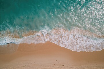 A drone shot reveals a peaceful shoreline bathed in gentle sunlight with waves softly washing ashore.