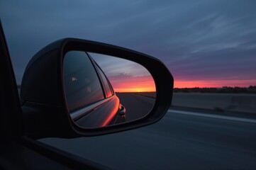 Driving Perspective on the Highway with a Sunset in the Rearview Mirror