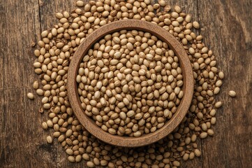 Camelina seeds promoting heart health and reducing cholesterol, enriched with vitamin E for skin care and anti-inflammatory effects, displayed on rustic wood from above.