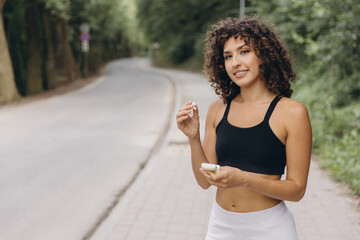 Young sportswoman inserting wireless earphones before running in a park