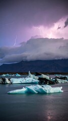 Dramatic icebergs illuminated by stormy sky