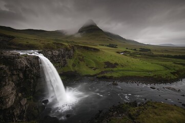 Fototapeta premium A cascading waterfall in a lush green setting