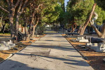Historic pathway lined with cannons and trees at Çimenlik Castle, Çanakkale, Turkey.
